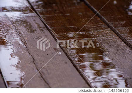 Rainwater Ripples Across Weathered Wooden Deck Boards Rainwater Ripples Across Weathered Wooden Deck Boards 142556103
