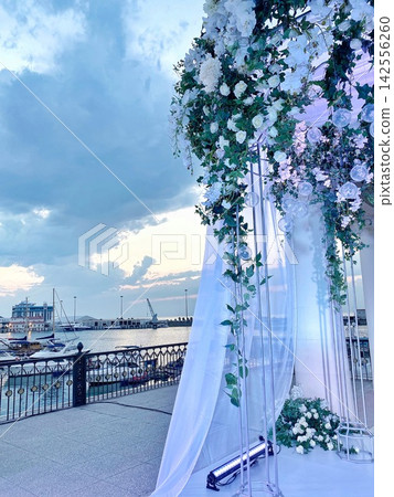 Wedding arch with flowers near marina at sunset, soft light, romantic atmosphere Wedding arch with flowers near marina at sunset, soft light, romantic atmosphere 142556260