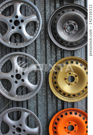 Front parts of steel and light alloy wheel rims of cars on a metal backdrop. Car parts painting stock image Front parts of steel and light alloy wheel rims of cars on a metal backdrop. Car parts painting stock image 142556312
