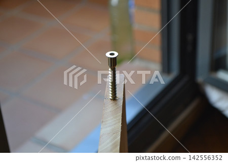Closeup screw in wooden plank near window for diy construction background and home repair detail Closeup screw in wooden plank near window for diy construction background and home repair detail 142556352