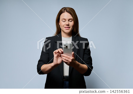 Business woman standing and typing on smartphone during online work or chat Business woman standing and typing on smartphone during online work or chat 142556361