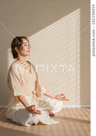 一位女性瑜珈教練在家練習瑜珈和冥想的圖片。 142556454