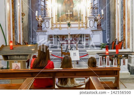 Young mother sitting with daughters in church Young mother sitting with daughters in church 142556500