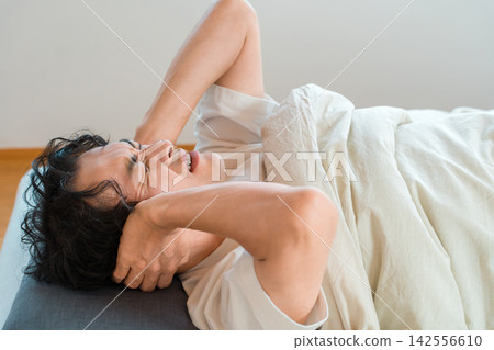 一名男子因噪音而睡眠受損,睡覺時會摀住耳朵。 一名男子因噪音而睡眠受損,睡覺時會摀住耳朵。 142556610