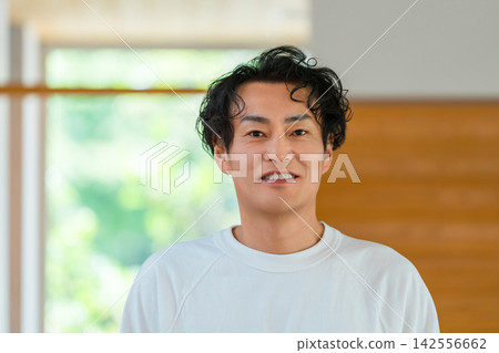 一位四十多歲、神采奕奕的男士在燈火通明的房間裡露出笑容。 一位四十多歲、神采奕奕的男士在燈火通明的房間裡露出笑容。 142556662