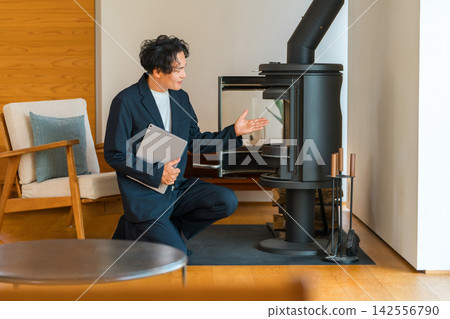 A male sales representative from a home builder explaining wood-burning stoves in a model home. A male sales representative from a home builder explaining wood-burning stoves in a model home. 142556790