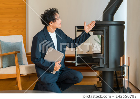 A male sales representative from a home builder explaining wood-burning stoves in a model home. A male sales representative from a home builder explaining wood-burning stoves in a model home. 142556792