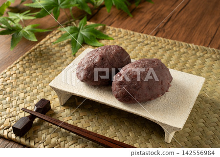An autumn Japanese sweet featuring ohagi (rice cake) filled with sweet red bean paste and garnished with a maple leaf. An autumn Japanese sweet featuring ohagi (rice cake) filled with sweet red bean paste and garnished with a maple leaf. 142556984