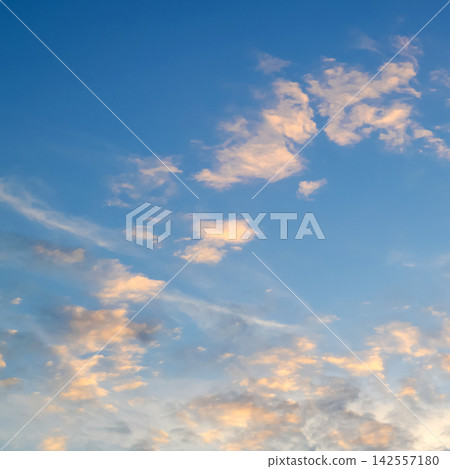 pastel pink and gold clouds scattered across a bright clear blue sky pastel pink and gold clouds scattered across a bright clear blue sky 142557180