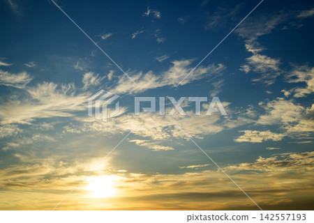 setting sun illuminates wispy clouds in the blue sky setting sun illuminates wispy clouds in the blue sky 142557193