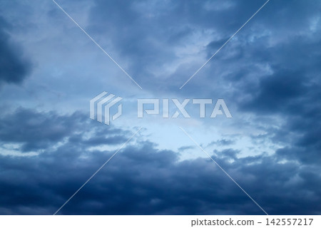 dense dark storm clouds with a light opening in the center dense dark storm clouds with a light opening in the center 142557217