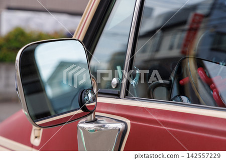 The side mirror of a red car and the reflection of the city. The side mirror of a red car and the reflection of the city. 142557229