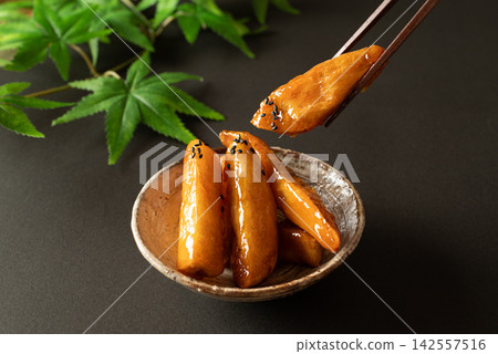 用筷子夾起一塊閃閃發亮的蜜餞紅薯 用筷子夾起一塊閃閃發亮的蜜餞紅薯 142557516