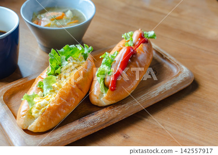 A set including coffee, hot soup, and two kinds of hot dogs served on a wooden tray. A set including coffee, hot soup, and two kinds of hot dogs served on a wooden tray. 142557917