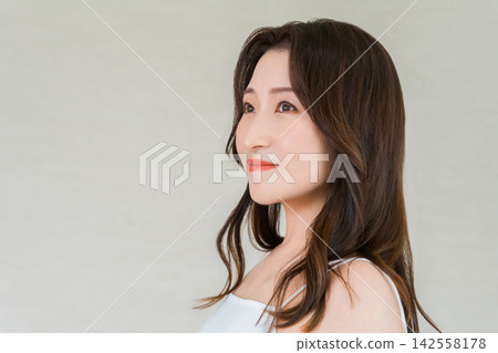 Hair care image of a woman in her 40s with beautiful, glossy hair and striking hair color. Hair care image of a woman in her 40s with beautiful, glossy hair and striking hair color. 142558178