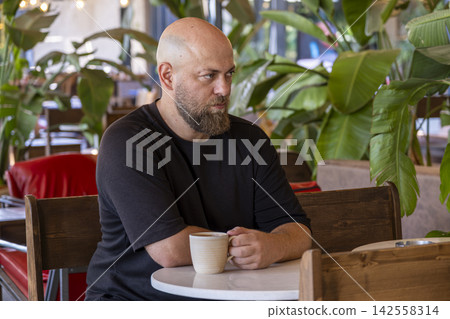 Male Customer Drinking Coffee at a Cafe. Male Customer Drinking Coffee at a Cafe. 142558314