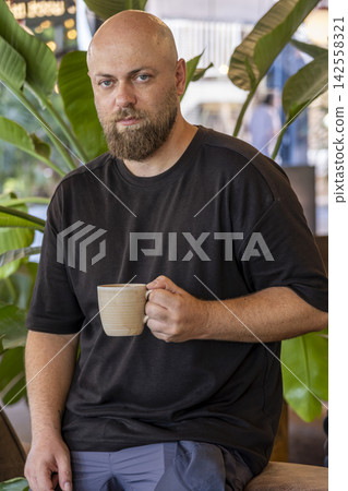 Male Customer Drinking Coffee at a Cafe. Male Customer Drinking Coffee at a Cafe. 142558321