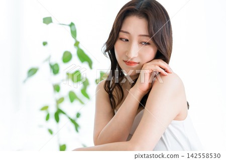 A 40-something woman with beautiful skin bathed in greenery and natural light. A beauty image of organic, natural skincare. A 40-something woman with beautiful skin bathed in greenery and natural light. A beauty image of organic, natural skincare. 142558530
