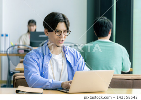 Business person using a computer in a cafe Business person using a computer in a cafe 142558542