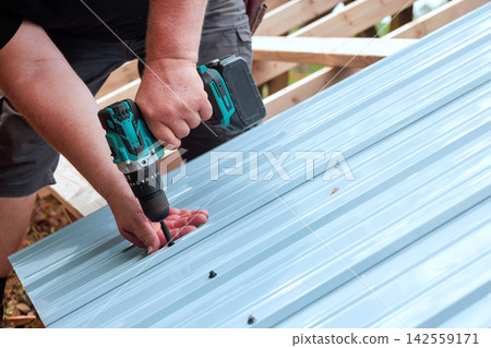 Person using power drill to attach metal sheets on construction project Person using power drill to attach metal sheets on construction project 142559171