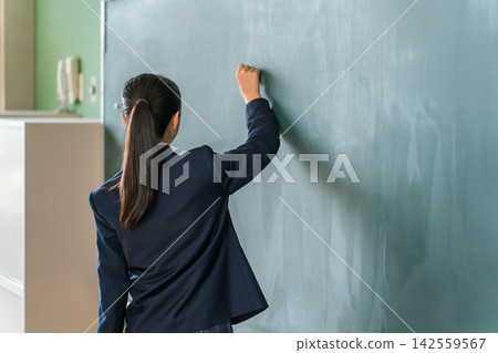 A high school girl writing on the classroom blackboard. This represents an image of school education, where students engage in lessons, studying, and problem-solving exercises. A high school girl writing on the classroom blackboard. This represents an image of school education, where students engage in lessons, studying, and problem-solving exercises. 142559567
