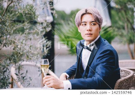 一位身穿燕尾服的男士手持酒杯。 一位身穿燕尾服的男士手持酒杯。 142559746