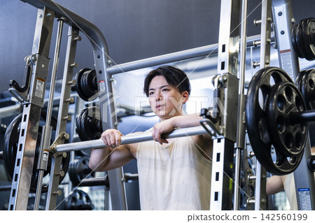 A young man doing barbell squats at the gym A young man doing barbell squats at the gym 142560199