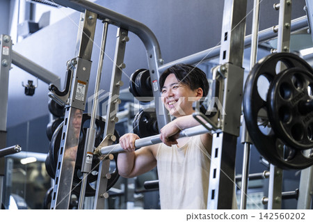 A young man doing barbell squats at the gym A young man doing barbell squats at the gym 142560202