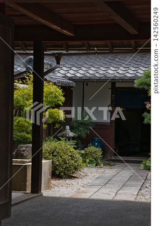 A view of the courtyard of a traditional townhouse in Omihachiman, seen through a wooden gate. A view of the courtyard of a traditional townhouse in Omihachiman, seen through a wooden gate. 142560249