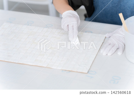 一位女士正在用膩子填滿瓷磚之間的縫隙——DIY 142560618