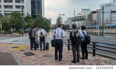 Office workers waiting at a traffic light at an intersection Office workers waiting at a traffic light at an intersection 142560926