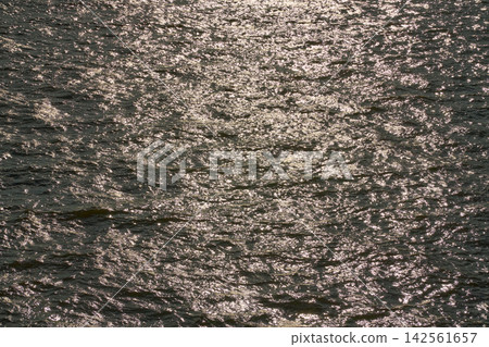 The texture of the rippling sea surface, shimmering golden in the setting sun. The texture of the rippling sea surface, shimmering golden in the setting sun. 142561657