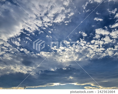 A dynamic backdrop of cumulus clouds and blue sky, interwoven with light and shadow. A dynamic backdrop of cumulus clouds and blue sky, interwoven with light and shadow. 142561664