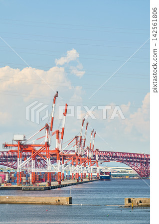 The gantry cranes of Osaka South Port and the Minato Ohashi Bridge stretch out under a midsummer sky filled with large, white cumulonimbus clouds. The gantry cranes of Osaka South Port and the Minato Ohashi Bridge stretch out under a midsummer sky filled with large, white cumulonimbus clouds. 142561806