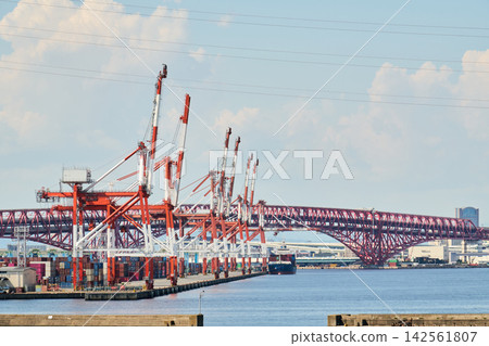 The gantry cranes of Osaka South Port and the Minato Ohashi Bridge stretch out under a midsummer sky filled with large, white cumulonimbus clouds. The gantry cranes of Osaka South Port and the Minato Ohashi Bridge stretch out under a midsummer sky filled with large, white cumulonimbus clouds. 142561807
