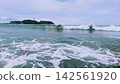 White waves crashing against the Shonan coast, with Enoshima Island visible in the distance. 142561920