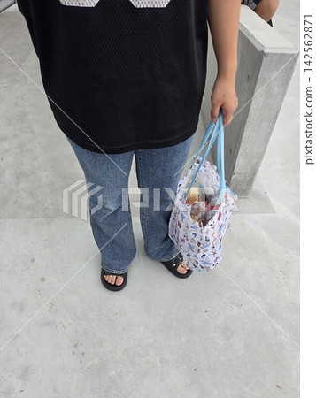 一位女士購物時使用環保袋,照片中可以看到她的背影。 一位女士購物時使用環保袋,照片中可以看到她的背影。 142562871