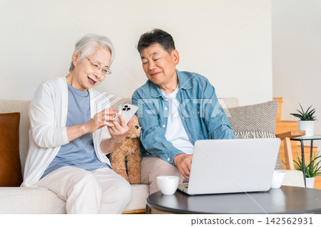 一對六、七十歲的老年夫婦，喜歡在家用智慧型手機和電腦上網。 142562931
