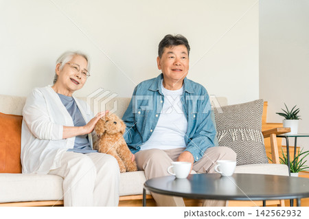 一對六、七十歲的老年夫婦在家中與心愛的狗狗一起享受悠閒時光。與寵物共度充實美好的退休生活,開啟人生第二春。 一對六、七十歲的老年夫婦在家中與心愛的狗狗一起享受悠閒時光。與寵物共度充實美好的退休生活,開啟人生第二春。 142562932