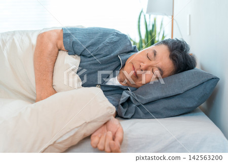 A senior man in his 60s or 70s sleeping in his bed at home. A bedroom lifestyle that evokes sleep, health, and restful sleep. A senior man in his 60s or 70s sleeping in his bed at home. A bedroom lifestyle that evokes sleep, health, and restful sleep. 142563200