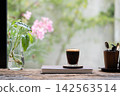 Small coffee mug and plant in a glass vase 142563514