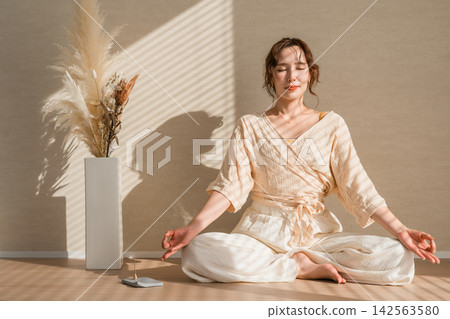 一位女子在晨光中冥想。她過著充實的生活,注重正念和身心健康。 一位女子在晨光中冥想。她過著充實的生活,注重正念和身心健康。 142563580