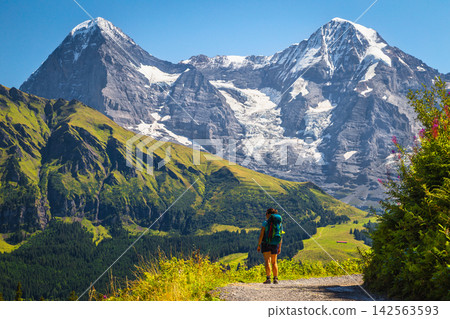 Hiker woman with backpack on the alpine trail, Murren, Switzerland Hiker woman with backpack on the alpine trail, Murren, Switzerland 142563593
