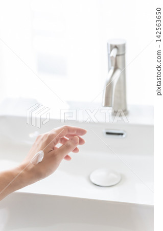 一位女士的手和手部護理:在乾淨的水槽邊,將潤膚霜塗抹在手背上。 一位女士的手和手部護理:在乾淨的水槽邊,將潤膚霜塗抹在手背上。 142563650