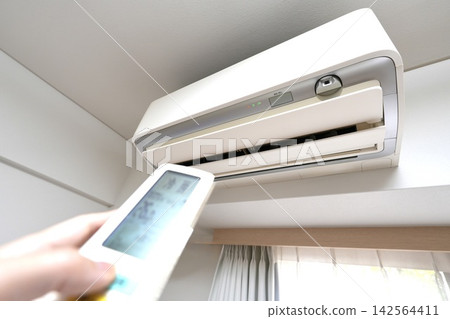 Image showing how to control the temperature and manage the air conditioning of a wall-mounted air conditioner in a room using a remote control. Image showing how to control the temperature and manage the air conditioning of a wall-mounted air conditioner in a room using a remote control. 142564411