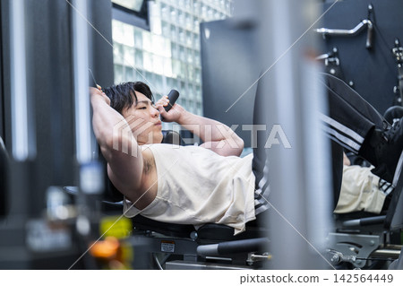 一位年輕男子在健身房進行腿部推舉訓練。 142564449