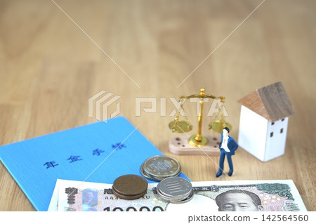 An image comparing mortgages and retirement funds, featuring a wood grain background, scales, a house model, Japanese yen, and a blue notebook. An image comparing mortgages and retirement funds, featuring a wood grain background, scales, a house model, Japanese yen, and a blue notebook. 142564560