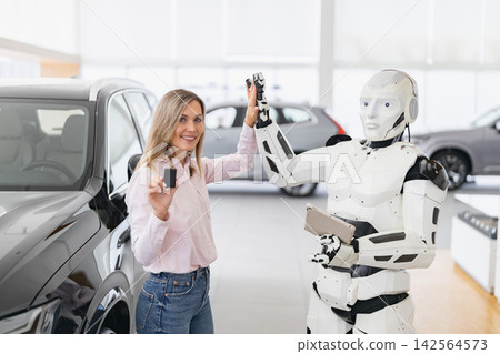 A woman and a humanoid robot high five in a modern car dealership showroom with vehicles in the background A woman and a humanoid robot high five in a modern car dealership showroom with vehicles in the background 142564573