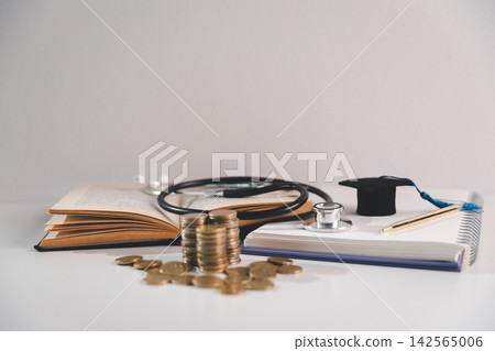 Coins, stethoscope, books, and graduation cap symbolize the financial cost of medical education, student expenses, healthcare careers, tuition, savings, and professional development. Coins, stethoscope, books, and graduation cap symbolize the financial cost of medical education, student expenses, healthcare careers, tuition, savings, and professional development. 142565006