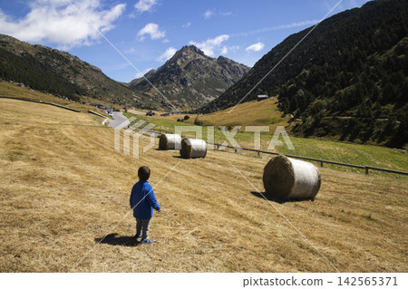 Child exploring pyrenees valley with hay bales Child exploring pyrenees valley with hay bales 142565371